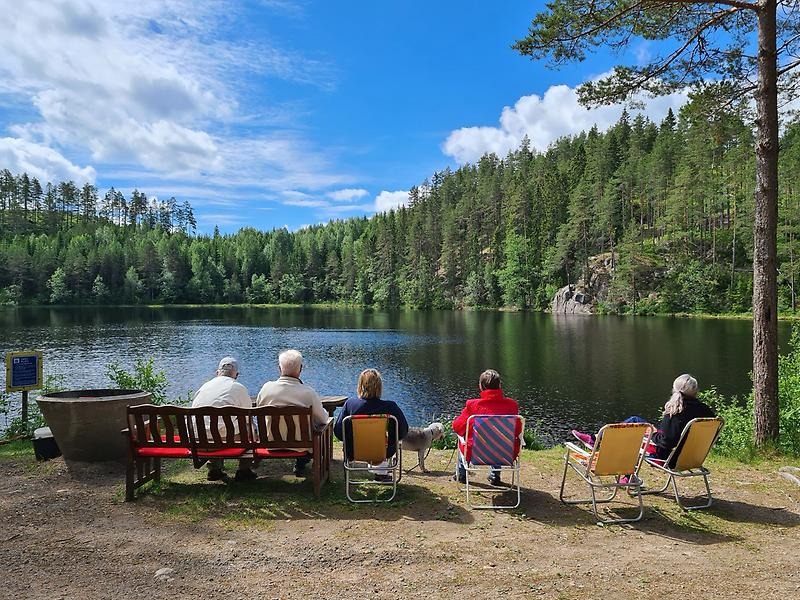 Pensionärer sitter vid en sjö och dricker kaffe