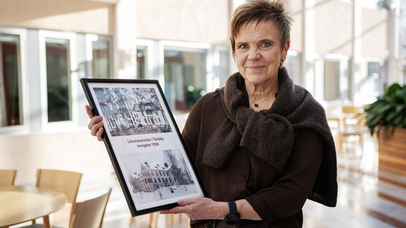 Områdeschef Britt-Louise Frykman med en tavla som visar hur sjukhuset såg ut 1924.