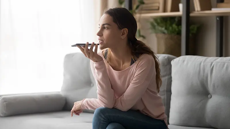 Orolig kvinna sitter i soffa och pratar i mobil