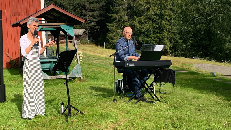En kvinna och man sjunger och spelar på en gräsplan.