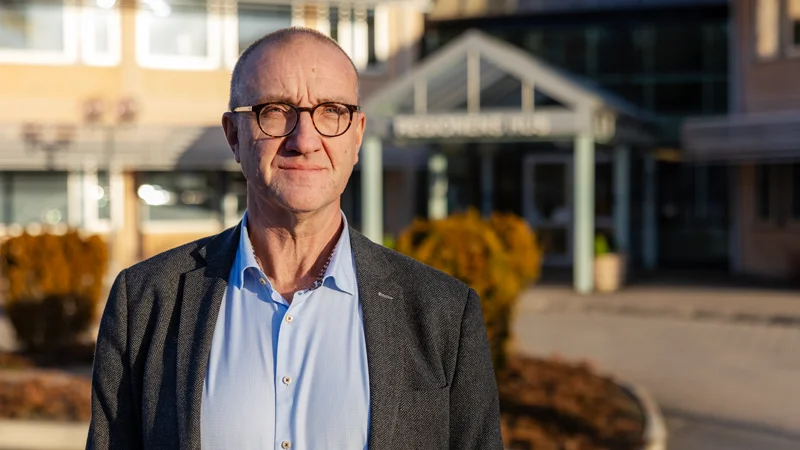 En porträttbild på regiondirektören. Han står utomhus med Regionens hus i bakgrunden.