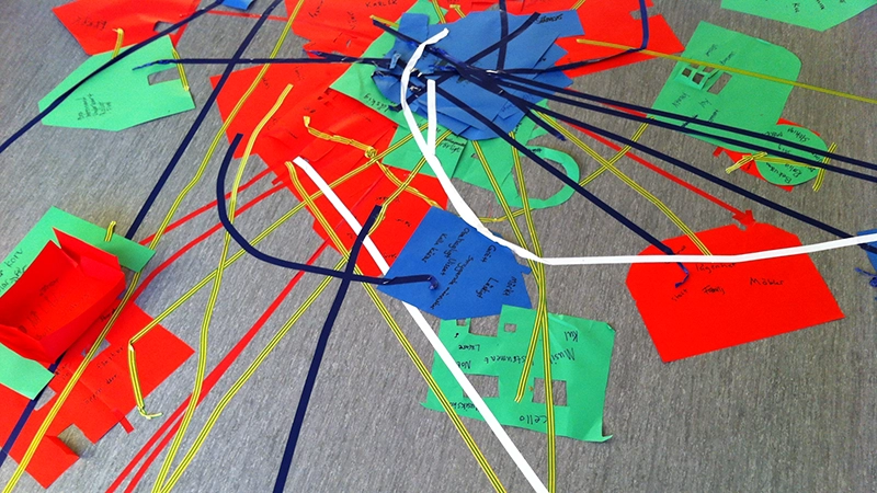 Färgade papper på ett golv med trådar mellan.