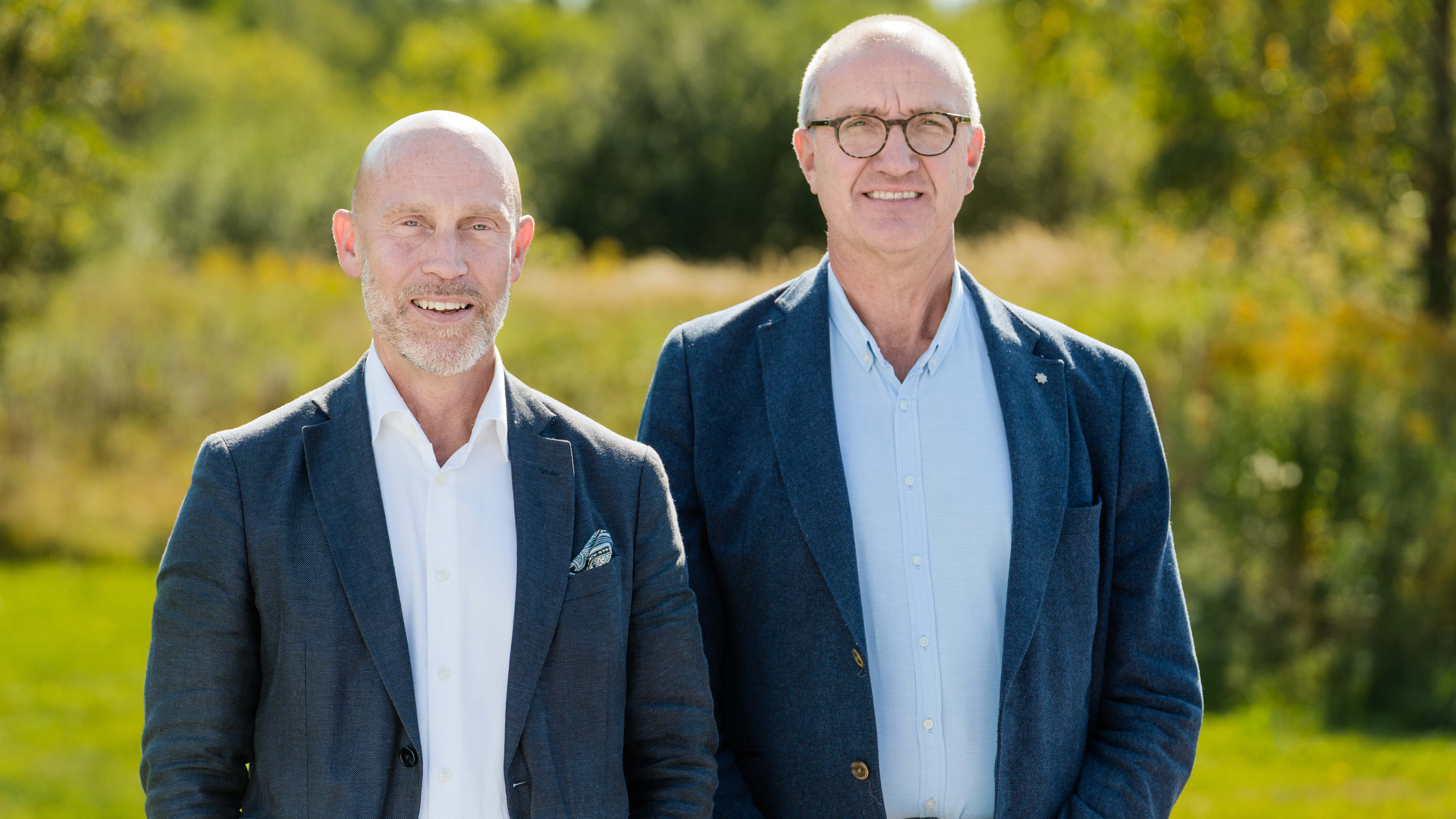 Två män står bredvid varandra och tittar in rakt in i kameran.