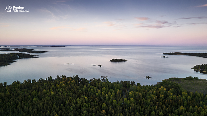 Sjön Vänern ovanifrån skog övergår i vatten som övergår i himmel sommartid.