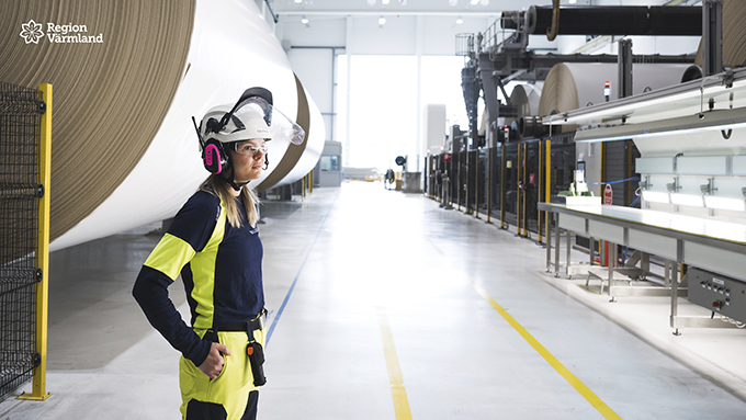 Kvinna i varselkläder står i en industrilokal