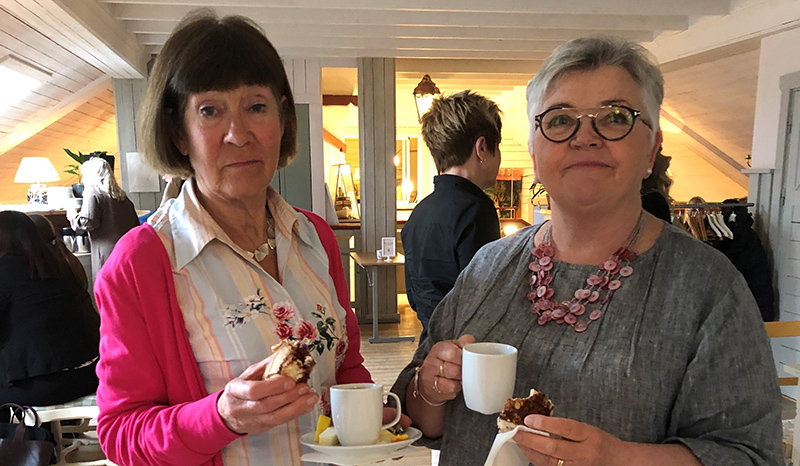 Två kvinnor bredvid varandra med kaffekopp i handen.