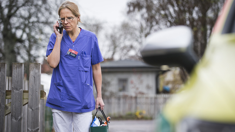Kvinnlig läkare pratar i mobiltelefon på väg till patient.