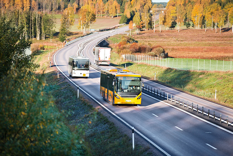 En gul buss som åker på en väg. Det är höstigt i luften