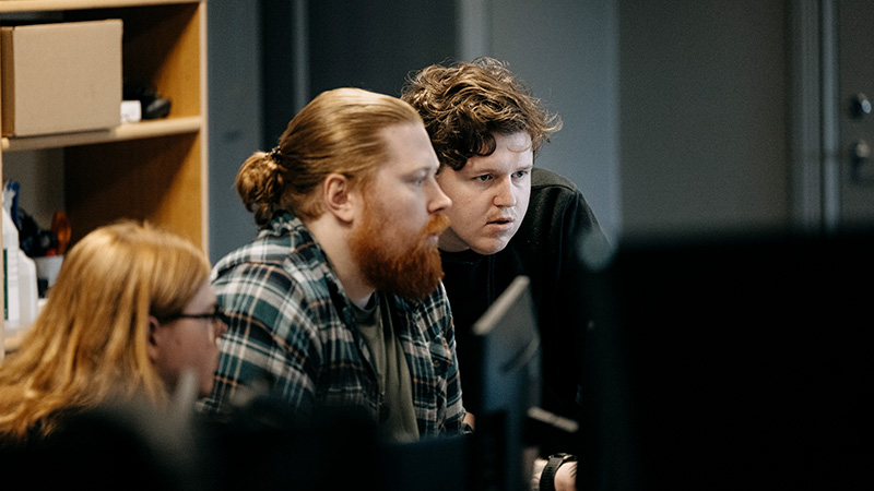 Tre personer framför datorskärmar