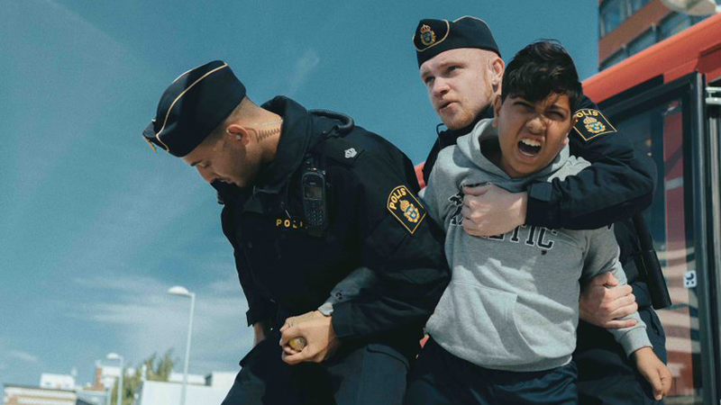 Pojke blir fasthållen av två poliser. © Clément Morin
