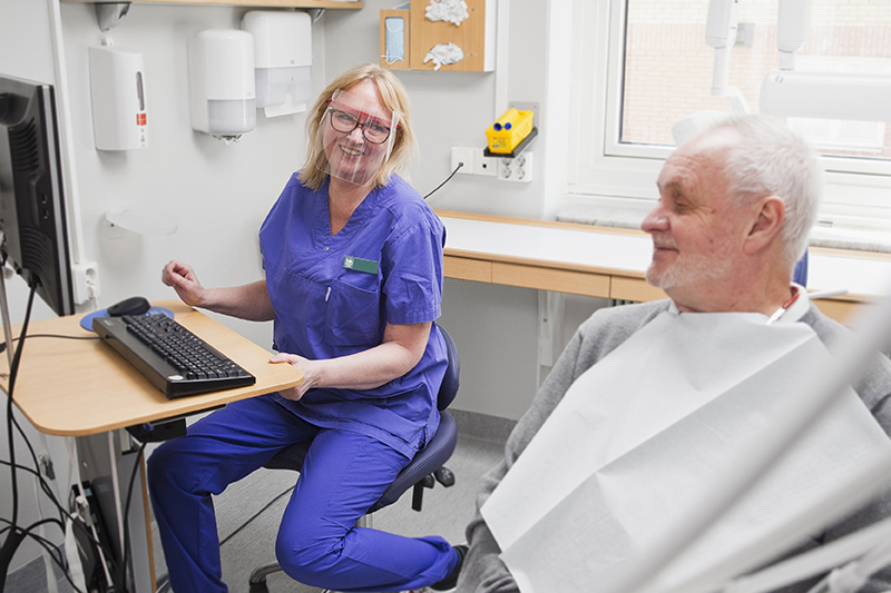 en behandlare sitter vid datorn och tittar på patienten i stolen