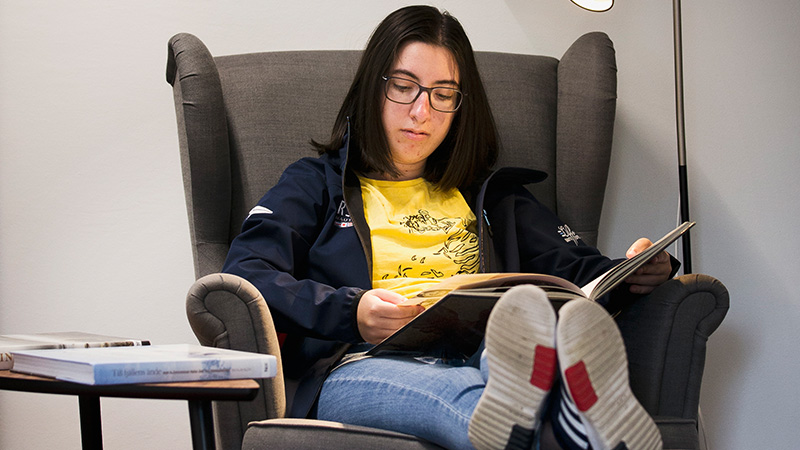 En person sitter och läser i en fåtölj.