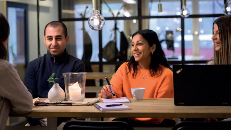 Fyra personer med positiv uppsyn kring ett bord