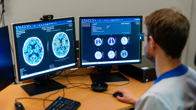 En av hälso- och sjukvårdens medarbetare sitter framför datorskärmar som visar röntgenbilder.