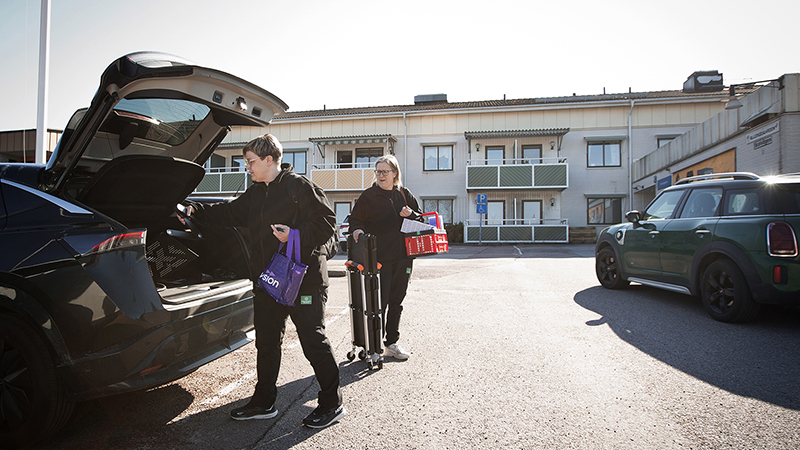 Mimmi och Tina packar ur bilen utanför ett äldre- och gruppboende