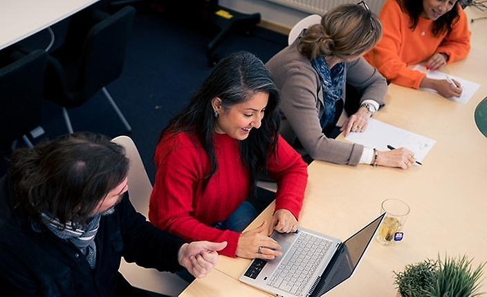 En man och en kvinna som sitter och pratar tillsammans, kvinnan skrattar.