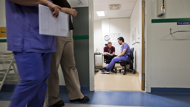 Två sittande personer tittar på ett på papper och pratar kring det.