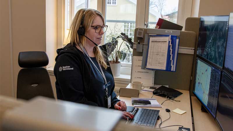 En larmoperatör med headset sitter vid sin skärm och pratar i telefon.