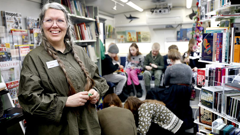 Kvinnlig bibliotekarie och barn i bokbuss.