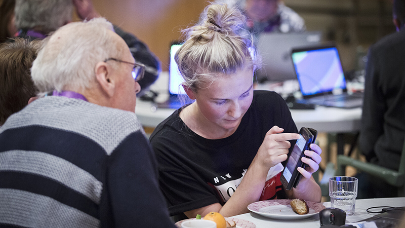 Äldre och ung tittar på en mobiltelefon.