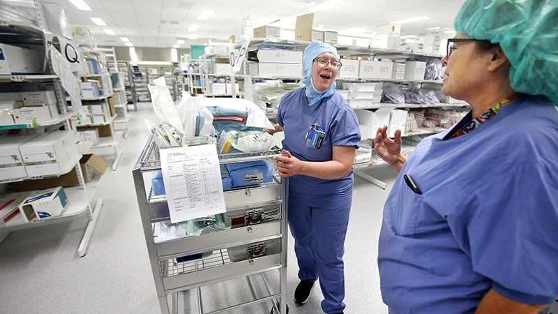 Två vårdkläddai ett förråd med sjukvårdsmateriel.