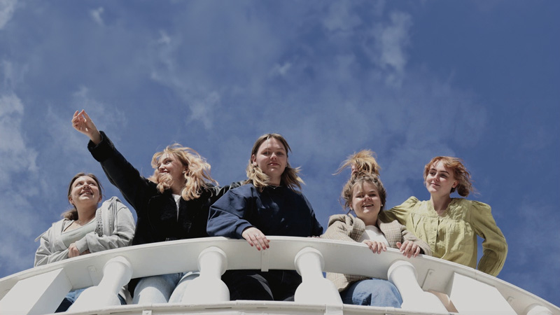 Fem unga kvinnor på en balkong.