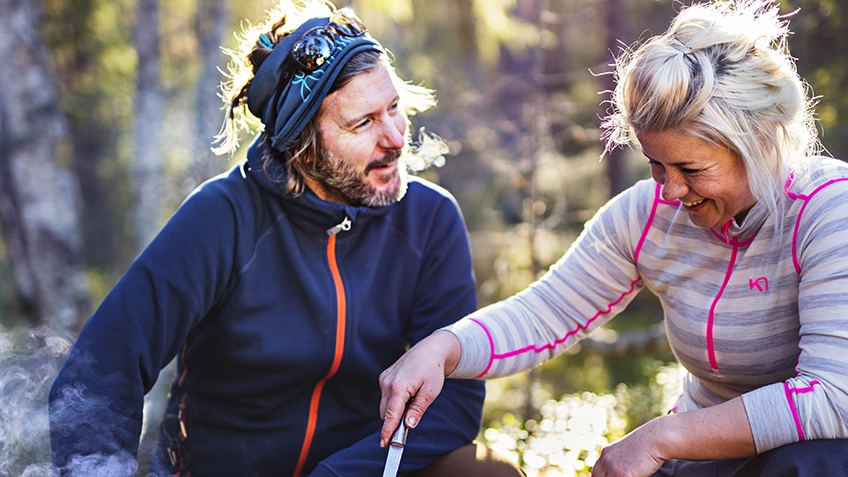 En man och kvinna i friluftskläder sitter i skogen. 