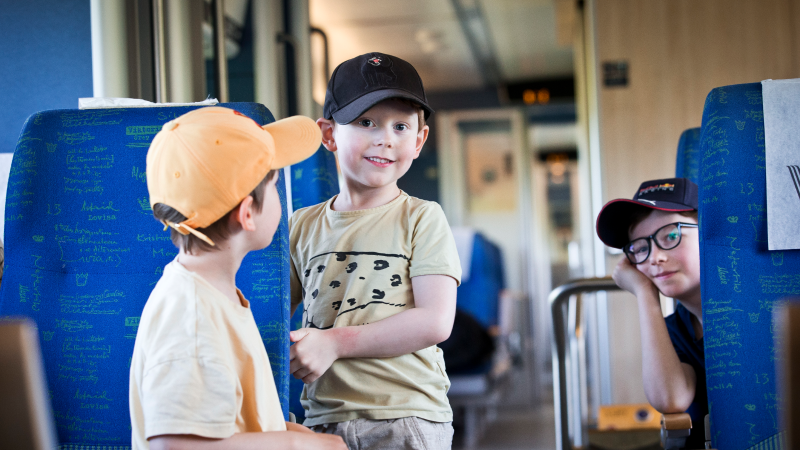 Tre pojkar som åker tåg.