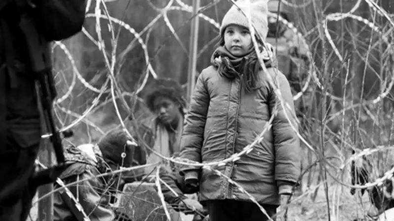 Tre barn vid stängsel.