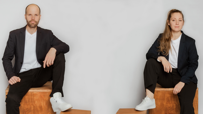 En man och en kvinna sitter på varsin trälåda.