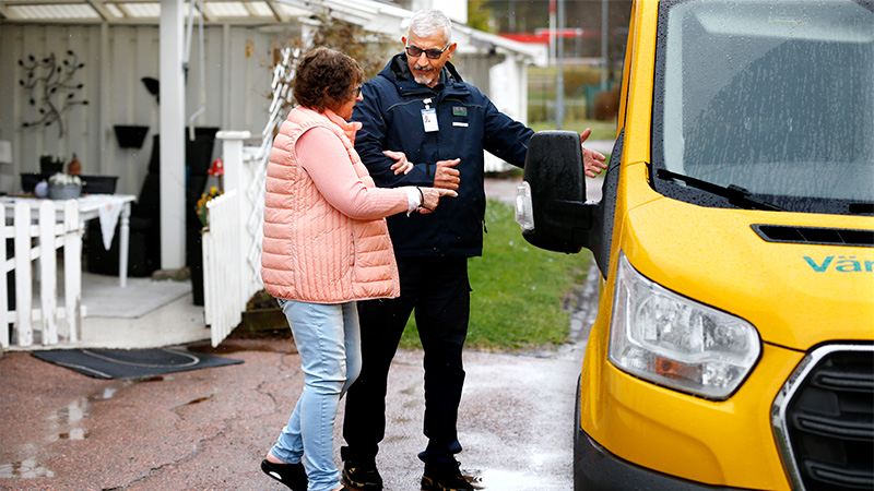 En förare inom servicetrafiken hjälper en kund ombord på ett gult servicetrafikfordon.