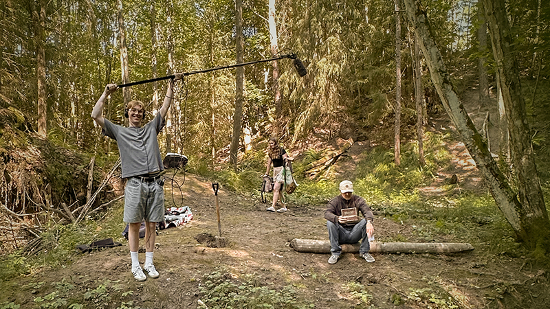 Tre ungdomar filmar i skogen