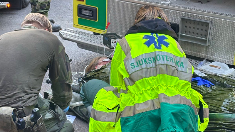 Försvarsmakten och ambulanssjukvårdare över och tar hand om fiktiv patient tillsammmans.