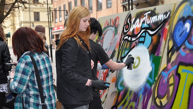 Några tonåringar målar med sprejburkar.
