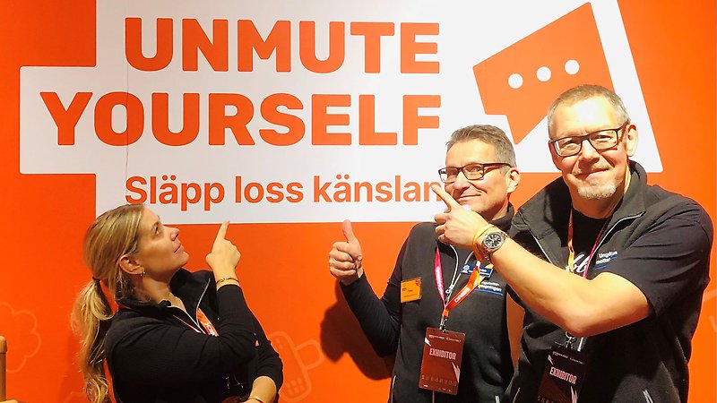 Tre personer pekar på en skylt