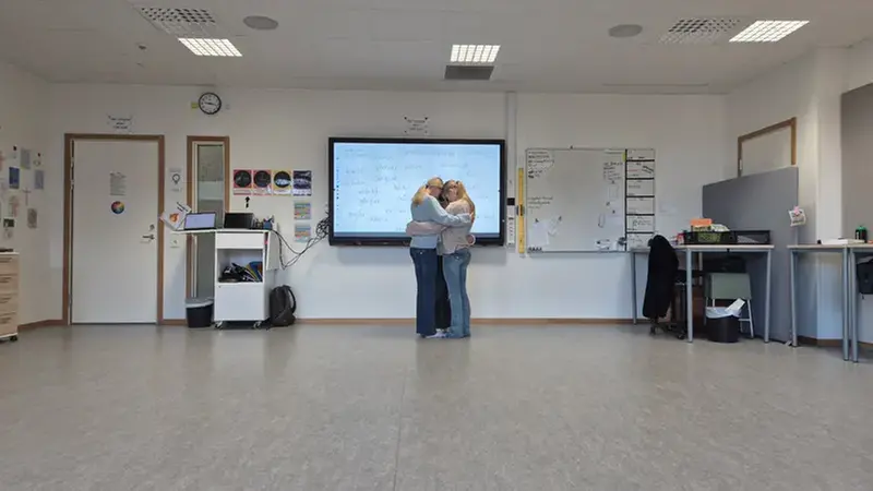 Tre tjejer i en gruppkram i ett klassrum.