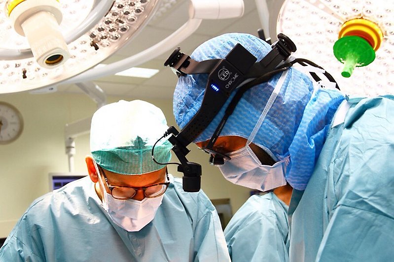 en grupp människor runt ett operationsbord klädda i operationskläder