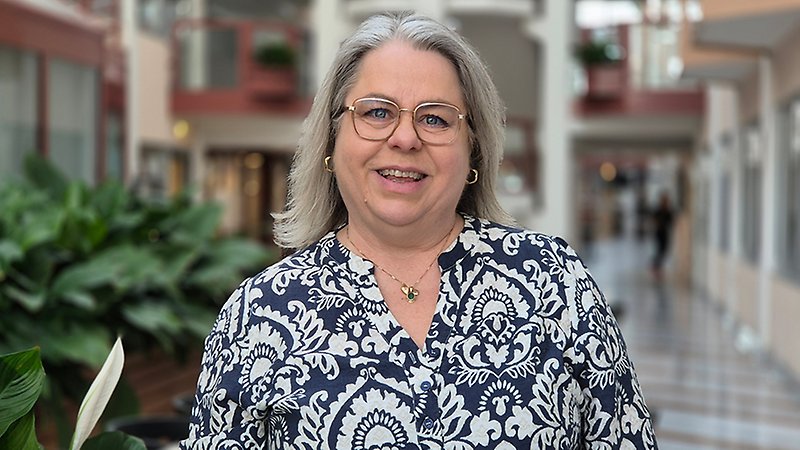 En kvinna ler och tittar in i kameran.