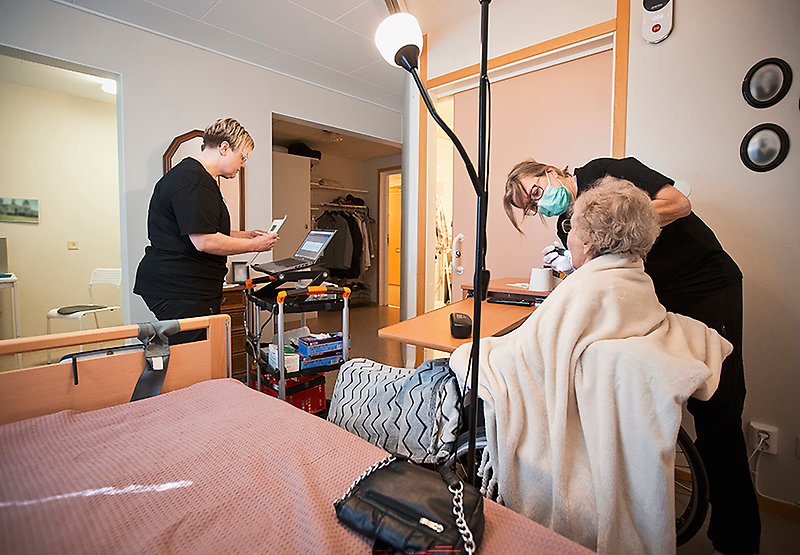 Mimmi skriver på datorn medan Tina undersöker patienten på sitt rum