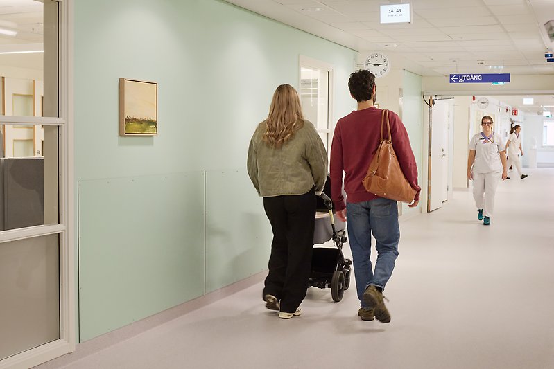 Ett par med barnvagn i sjukhuskorridor.