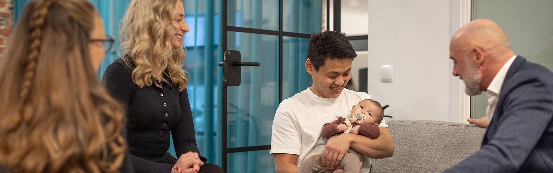 Glada personer runt bebis i kontorsmiljö.