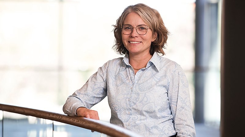 En kvinna tittar in i kameran och ler.